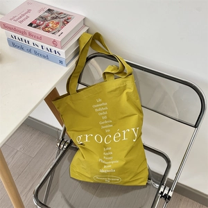 Gros plan d'un sac de shopping jaune avec texte floral sur une chaise transparente