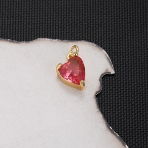 Detail of a gold-plated heart pendant with a pink zircon stone and top hanging ring