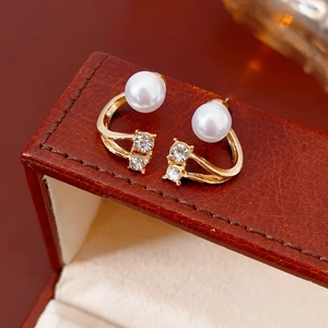 Vue détaillée des boucles d'oreilles perles dorées et cristaux sur coffret cuir