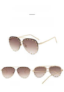 Detailed view of metal half-frame pilot sunglasses with gold rivets and tea gradient lenses