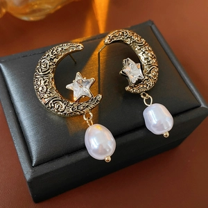 Macro detail of vintage gold crescent moon earrings with star diamonds and pearls