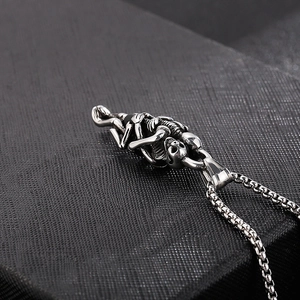 Detailed close-up of retro stainless steel pendant featuring two skulls in a tight embrace