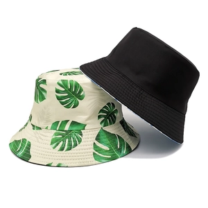 Detail of reversible bucket hats in tropical monstera leaf print and solid black cotton
