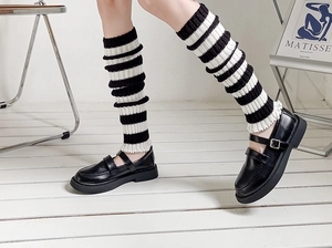 Detail of striped knit leg warmers with ruffle trim and black Mary Jane shoes