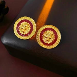 Detailed macro view of vintage lion head earrings with red enamel and Greek key pattern