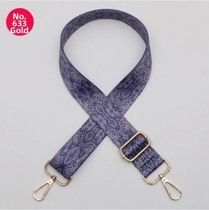 Detail of adjustable canvas bag strap with blue snake pattern and gold metal hooks