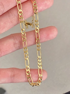 Detail shot of a golden Figaro link necklace showing the classic chain structure