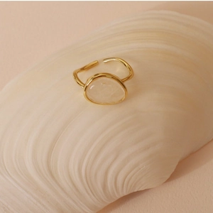Detail of a gold adjustable ring with an oval white crystal set in a natural shell