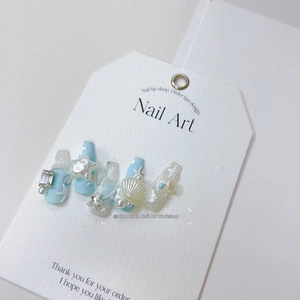 Detail showing ocean-themed handmade press-on nails with pearls, starfish and shells