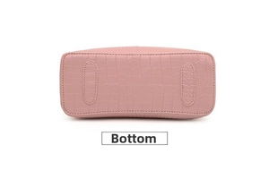 Detailed macro view of crocodile embossed leather bottom on pink crossbody bag