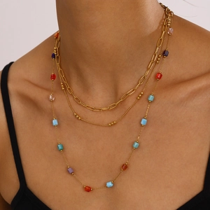 Detail of a layered gold necklace featuring paperclip chain and colorful square glass beads