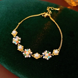 Detailed macro view of vintage gold flower bracelet with colorful gems on green velvet