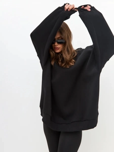 Detailed view of oversized black crewneck sweatshirt with ribbed cuffs and soft cotton texture