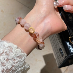 Detail view of strawberry quartz and agate beaded bracelet with gold vintage centerpiece
