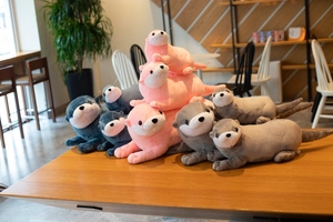 Close-up of cute plush otter dolls in various colors resting on a wooden cafe table