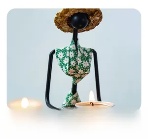 Détail macro du bougeoir en fer artisanal avec chapeau de paille et écharpe
