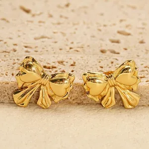Minimalist 18K gold bow knot stud earrings in stainless steel on stone background