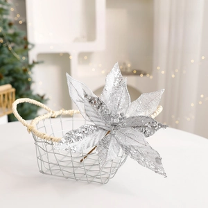 Fleur de poinsettia argentée pailletée pour sapin de Noël dans un panier blanc rustique