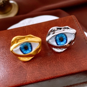 Detail of surrealist gold and silver rings with realistic blue eye resin designs