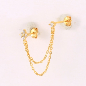 Detail of gold-tone chain tassel earrings with flower stud and white zircon accents