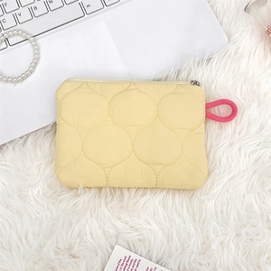 Quilted fabric pouch detail showing soft yellow texture and pink zipper knot pull