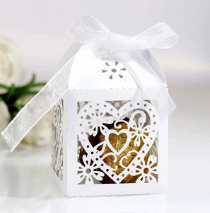 Close-up of white laser-cut heart favor box with elegant satin ribbon bow detail