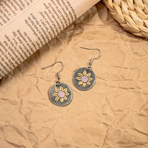 Detail of bohemian sunflower earrings with pink glitter center on retro metal base