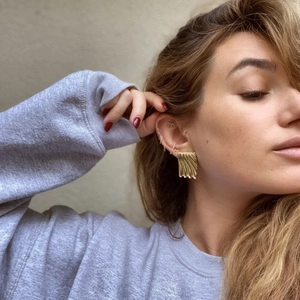 Detail of 18k gold plated textured rectangle earrings worn by a model in a close-up view