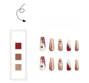 Close-up of autumn maple leaf press-on nails with dark red glitter and rhinestones