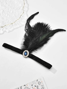 Detail of 1920s black feather headband featuring a blue gemstone and crystal ornament
