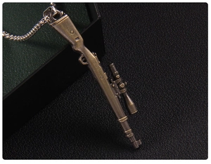 Macro detail of bronze submachine gun pendant with vintage finish on black leather