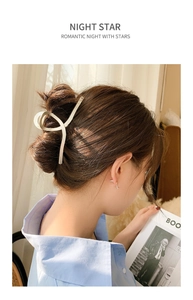 Detail view of a matte metallic claw clip with twisted design on a woman's hair