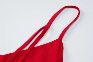 Detailed close-up of red knit jumpsuit straps and precision stitching craft