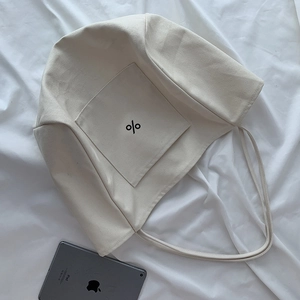 Detail view of cream white canvas tote bag with front pocket and bold black symbol print