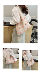 Detail of hand-knitted cream tote bag with delicate 3D pink crochet floral pattern