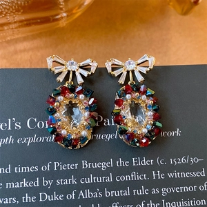 Detail of vintage bow earrings with colorful crystals and pearls on a retro background