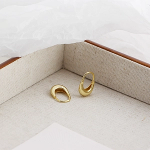 Minimalist gold U-shaped earrings displayed on a soft beige linen jewelry tray