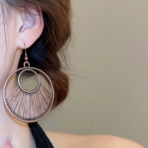 Close-up of vintage bronze geometric hollow earrings with woven silk thread detail