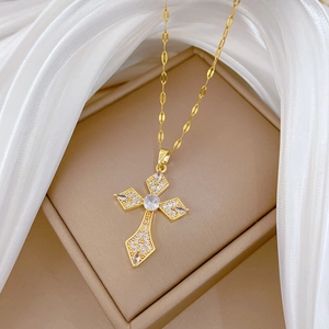 Macro view of a gold-plated titanium steel cross pendant with cubic zirconia on silk