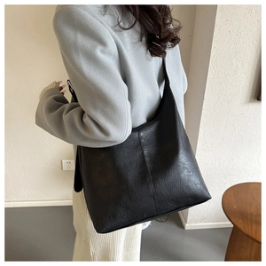 Minimalist black faux leather tote bag shown on model with spacious commuter design