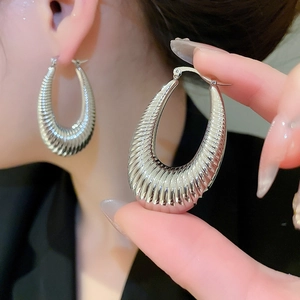 Close-up of silver-toned textured croissant earrings featuring horizontal striped patterns