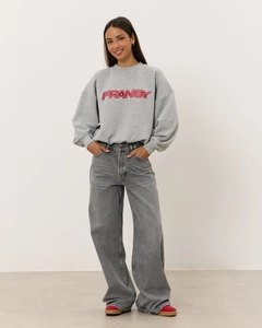 Détail d'un sweat-shirt gris vintage avec broderie de lettres FRANSY rouges sur la poitrine