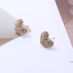 Macro shot of gold heart earrings with sparkling rhinestones on minimalist background