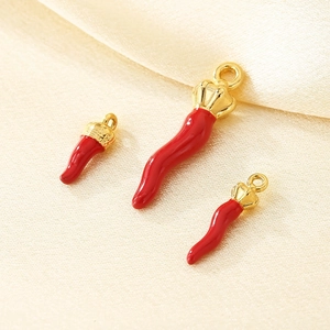 Detailed view of three red chili pendants with gold bases on beige silk fabric