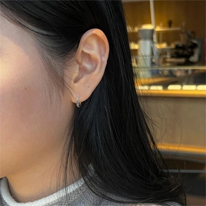 Close-up of minimalist sterling silver hexagonal ear hoop worn by a model
