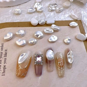 Macro detail of trapezoid nails with gold lines, irregular pearls and pink rhinestone