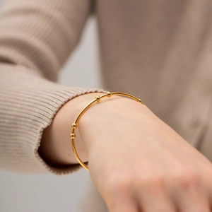 Minimalist 18K gold stainless steel bangle with five small golden beads on a female wrist