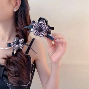 Detailed view of houndstooth fabric flower hair clip with black ribbon and pearls