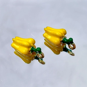 Detail of yellow bell pepper enamel charms with gold hooks for DIY jewelry crafting