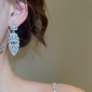 Detail of silver drop earrings with marquise-cut zircons worn on a model for a luxury look